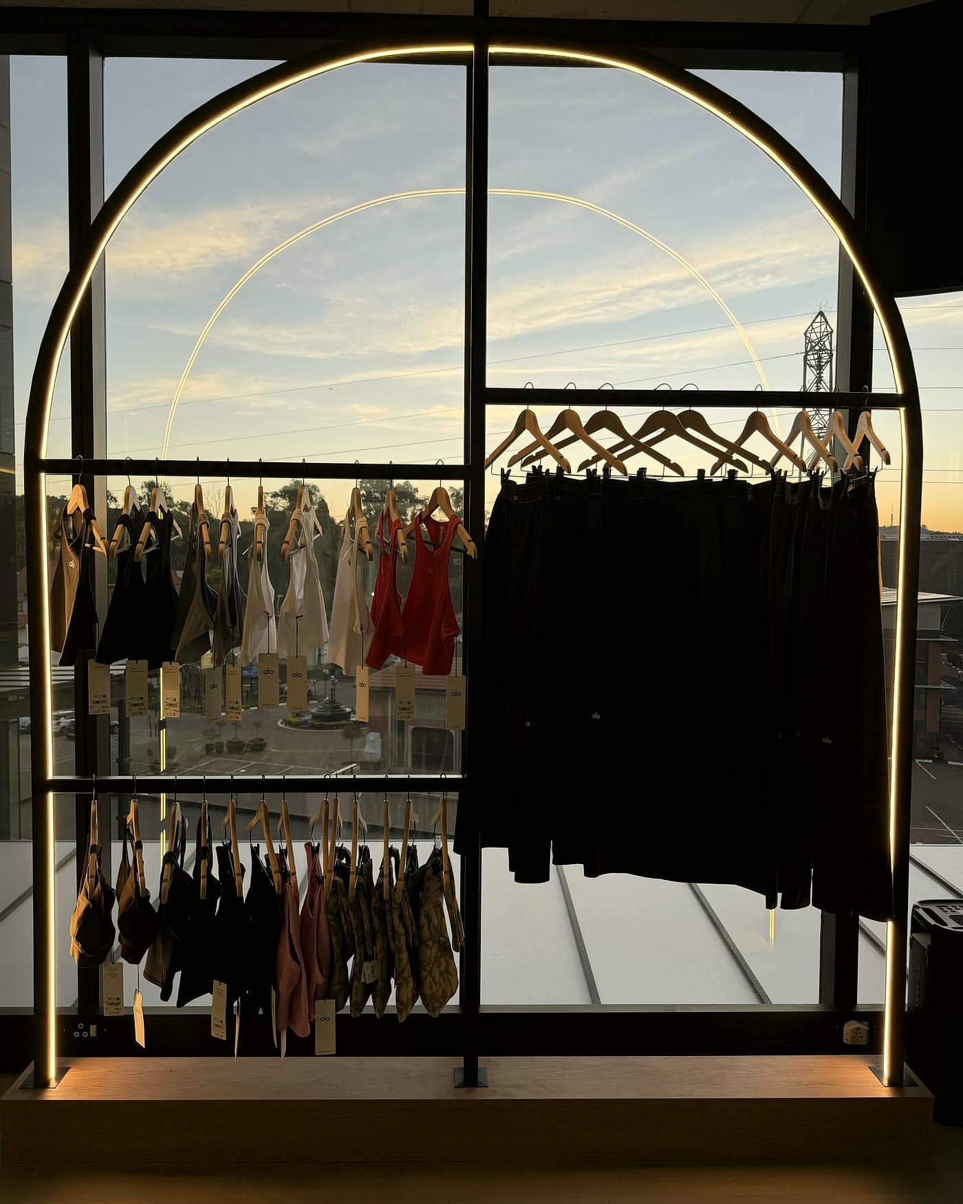 Activewear rails beneath the brass arch at dusk